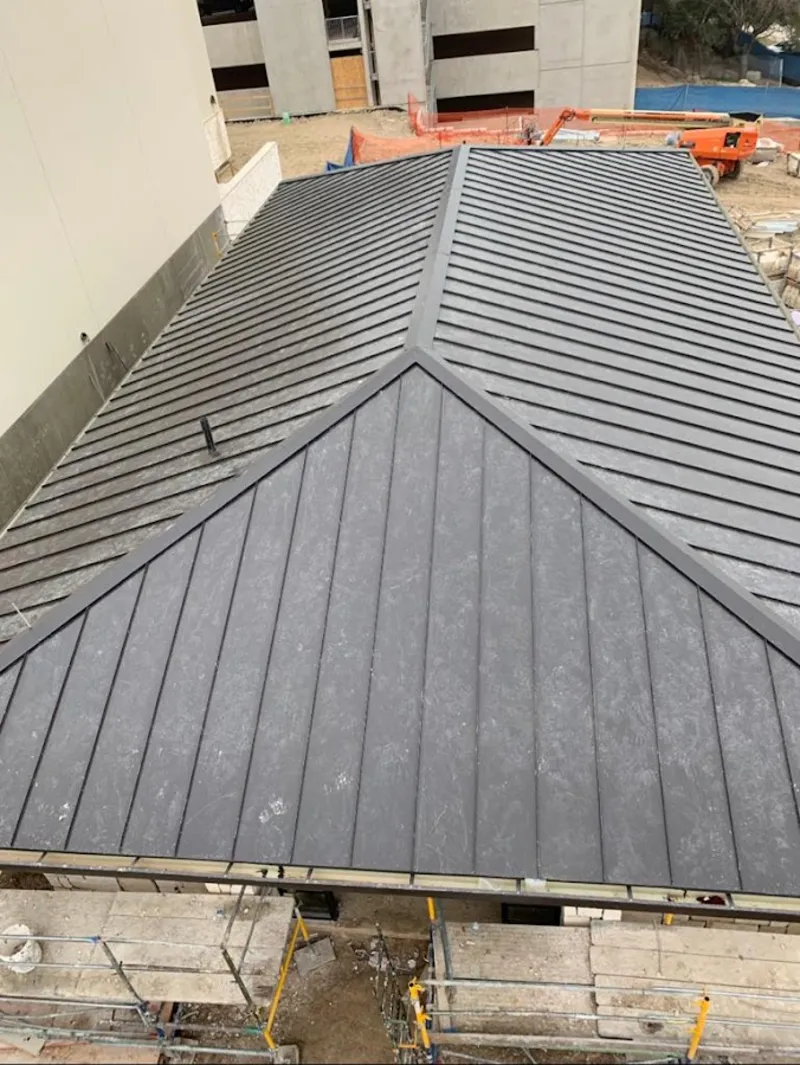 Commercial metal roof construction with crane equipment in Baxter